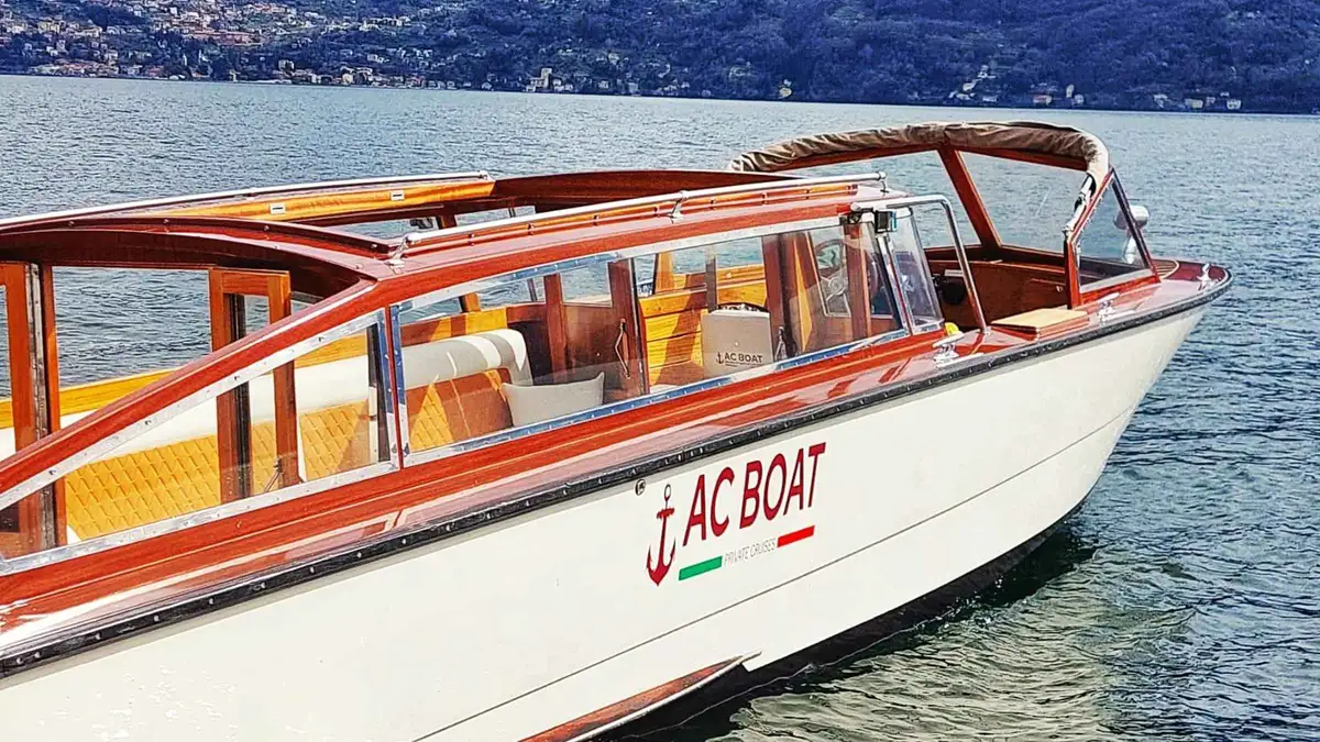 Wooden limousine boat leaving Menaggio on a central Lake Como villa cruise
